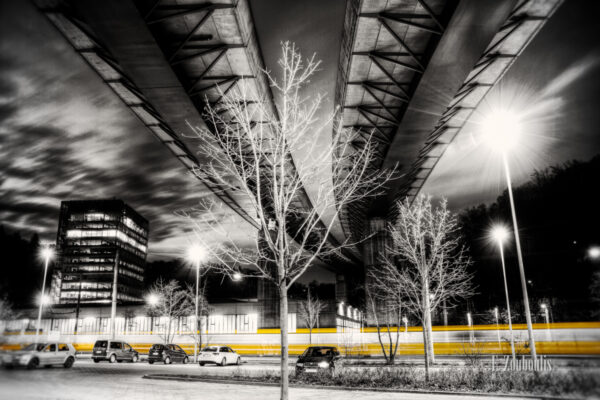 Unter der Brücke in Südheim. Bild in Schwarzweiss mit einer vorbeirauschenden Strassenbahn in gelber Farbe