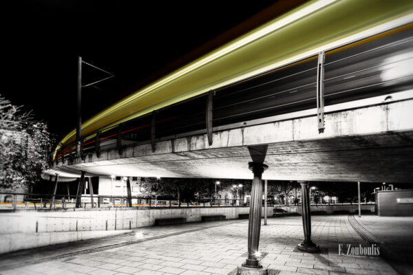 Bild am Marienplatz in Schwarzweiss mit gelbem Lichtschweif der vorbeiziehenden Zahnradbahn