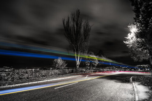 Bild in Schwarzweiss mit farbigem Lichtschweif des vorbeiziehenden Verkehrs.