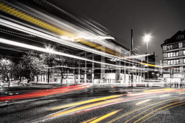 Schwarzweiss-Aufnahme des vorbeiziehenden Verkehrs mit farbigem Lichtschweif am Karlsplatz