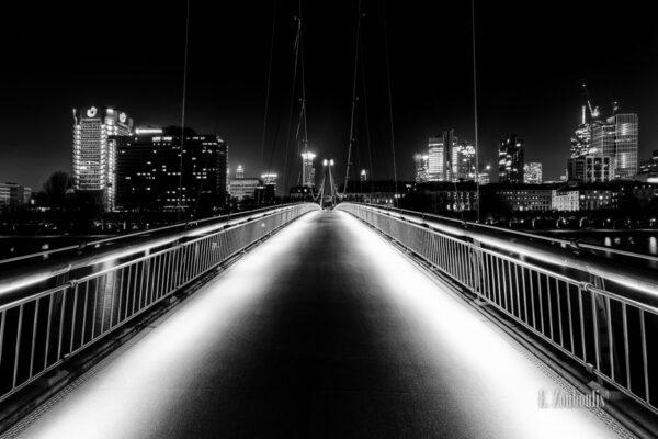 Schwarzweiss--Aufnahme auf der Brücke am Schaumainkai in Frankfurt und der Frankfurter Skyline im Hintergrund