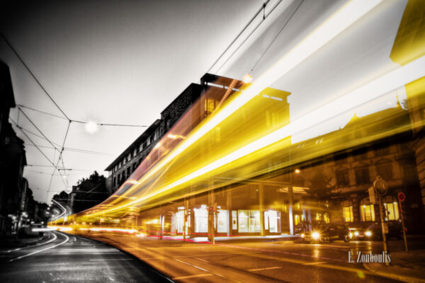 Schwarzweiss-Aufnahme am Generationenhaus in Heslach mit einer vorbeiziehenden Strassenbahn als Lichtschweif in gelb