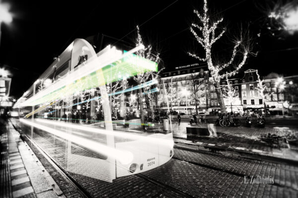 Schwarzweiss-Aufnahme einer Tram mit farbigem Lichtschweif in Amsterdam