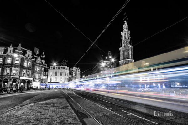 Schwarzweiss-Aufnahme am Muntplein, Amsterdam mit einer vorbeirauschenden Tram in Form eines farbigen Lichtschweifs