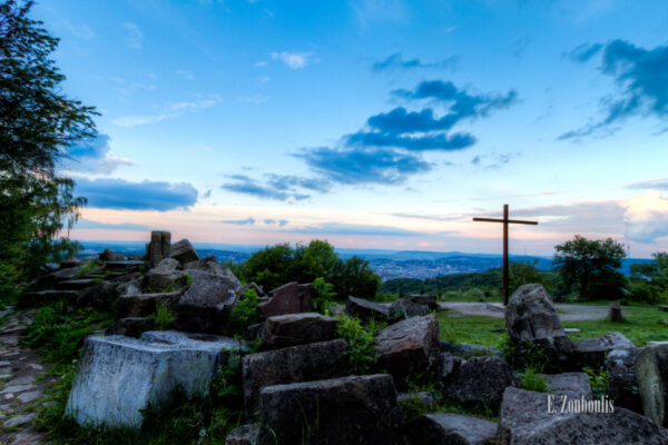 Aufnahme zum Sonnenuntergang auf dem Birkenkopf in Stuttgart. Im Vordergrund und links die Steine, die als Mahnmal gelten, rechts im Bild das große Kreuz und im Hintergrund Stuttgart und der Fernsehturm