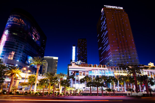 Aufnahme zur späten blauen Stunde auf dem Las Vegas Strip in Las Vegas, Nevada, USA. Im Vordergrund sind die Straße und Palmen zu sehen und im Hintergrund das Cosmopolitan Hotel und Casino