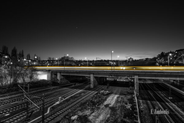 Schwarzweiß-Aufnahme am Nordbahnhof einer vorüberziehenden Straßenbahn mit einem gelben Lichtschweif