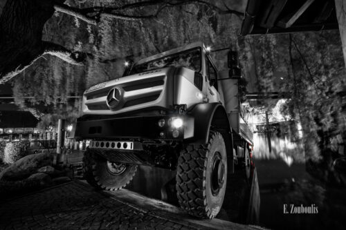 Schwarzweiß-Aufnahme eines Unimog eingetaucht in den See des Europa Park mit roten Elementen, die die Rücklichter Kennzeichnen