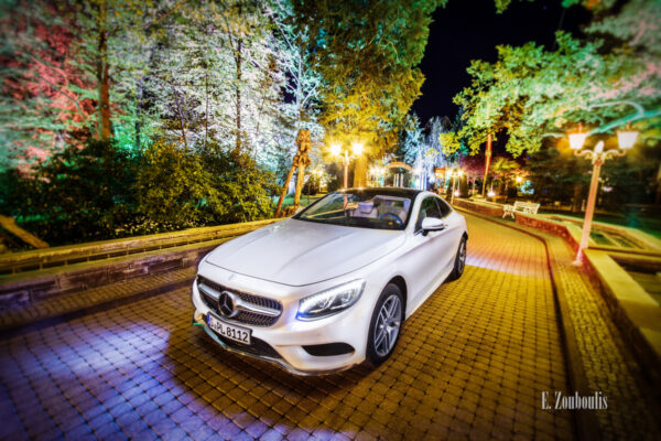 Nacht-Aufnahme einer weißen Mercedes S-Klasse im Europapark, umgeben von Bäumen