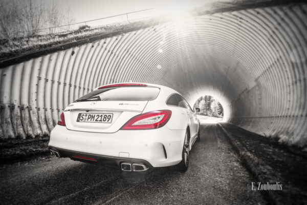 Schwarzweiß-Aufnahme eines Mercedes Benz CLS63 AMG vor einem Tunnel mit roten Elementen