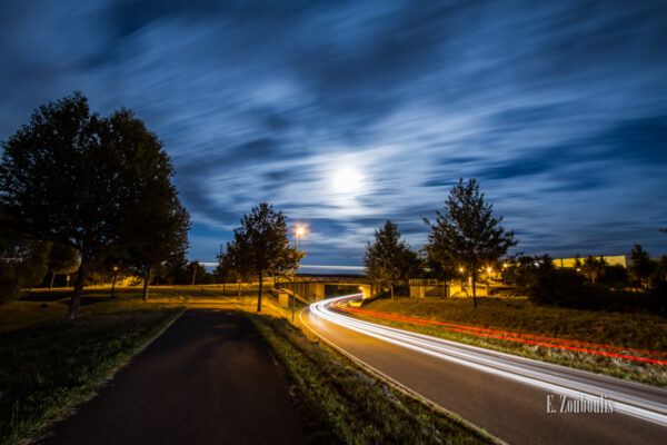 Nachtaufnahme in Gärtringen. Ein rot / weißer Lichtschweif verschwindet unter der Brücke, auf der ein Zug ebenfalls einen Light-Trail hinterlässt