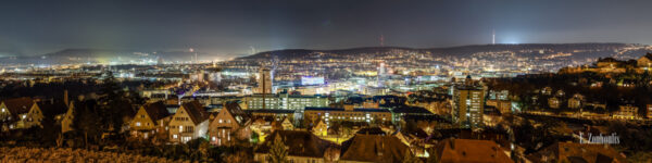 Panorama Aufnahme bei Nacht mit Blick über die Innenstadt von Stuttgart. In der Mitte des Bildes befindet sich die Stadtbibliothek. Links im Hintergrund der Gasturm und rechts auf dem Berg der Fernsehturm