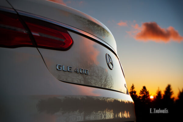 Die untergehende Sonne und die Nadelbäume des Schwarzwalds spiegeln sich am Heck eines Mercedes GLE