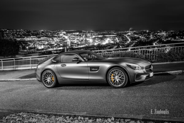 Schwarzweiß Aufnahme mit farbigen Elementen eines Mercedes Benz AMG GTS an der Wielandshöhe (Alte Weinsteige) in Stuttgart mit Blick auf die Stuttgarter Innenstadt von oben.