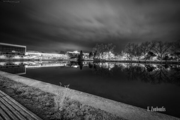 Schwarzweiß Aufnahme bei Nacht am See in Böblingen. Links im Bild die Kongresshalle, die sich im Wasser spiegelt