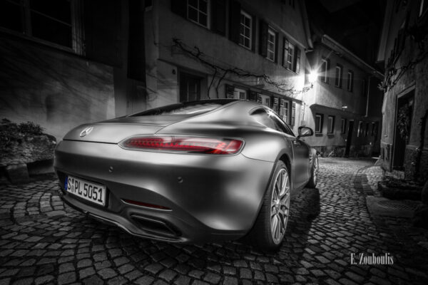 Schwarzweiß Aufnahme mit roten und blauen Elementen eines Mercedes AMG GTS in der Altstadt von Esslingen bei Nacht. Im Vordergrund das Heck des AMG auf dem Pflasterstein und im Hintergrund die charakteristischen Häuser Esslingens. Bild entstanden auf Einladung von Mercedes Benz