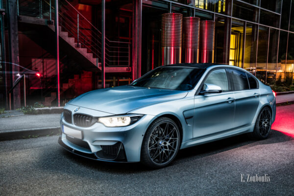 Nachtaufnahme eines BMW M3 in Stuttgart-Vogelrain. Blick seitlich auf die Front des M3. Im Vordergrund der BMW, im Hintergrund spiegelt sich das Fahrzeug an der Glasfassade des Kubus360 Gebäudes