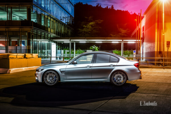 Nachtaufnahme eines BMW M3 in Stuttgart-Vogelrain. Blick seitlich auf den M3. Im Vordergrund der BMW, im Hintergrund das Gebäude des Kubus360 und der Torwiesenschule