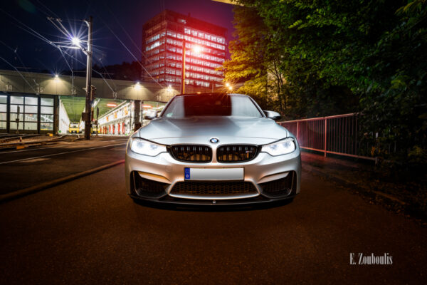 Nachtaufnahme eines BMW M3 in Stuttgart-Vogelrain. Blick frontal auf den M3. Im Vordergrund der BMW, im Hintergrund das Straßenbahn Depot Heslach und das Gebäude des Kubus360