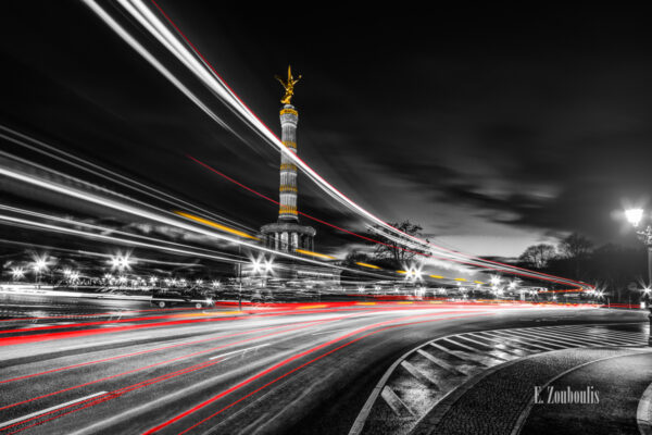 Schwarzweiß Aufnahme an der Siegessäule in Berlin mit roten und gelben Elementen, die den vorbeifahrenden Verkehr und die Berliner Siegessäule kennzeichnen