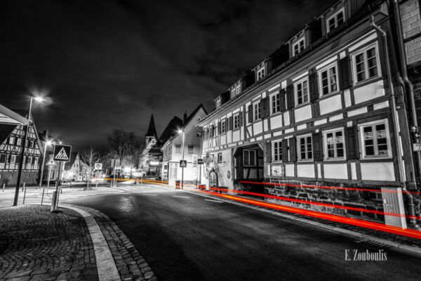 Schwarzweiß Aufnahme nachts in Gerlingen, Stuttgart mit roten Lichtschweifen, die den Verkehr sichtbar machen. Blick von der Kirchstraße auf die Weilimdorfer Straße