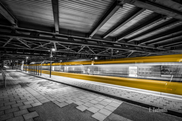 Schwarzweiß-Aufnahme am Nordbahnhof Stuttgart. Die vorbeifahrende Stadtbahn hinterlässt einen gelben Lichtschweif