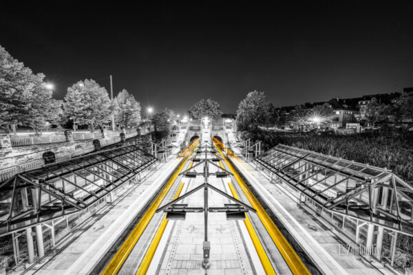 Schwarzweiß-Aufnahme am Pragsattel in Stuttgart. Die gelben Lichtschweife machen die ein- und die ausfahrenden Stadtbahnen sichtbar.