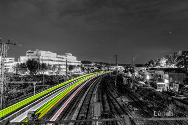 Schwarzweiß-Aufnahme in Stuttgart-Feuerbach mit grünen und roten Lichtschweifen, die die vorbeifahrenden Züge in der Nacht sichtbar machen