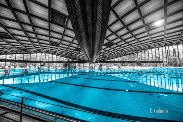 Schwarzweiß Aufnahme im Inneren des Badezentrum Sindelfingen. Das Wasser in den Becken ist in blau zu sehen. Seitliche Ansicht auf das 50m Becken.