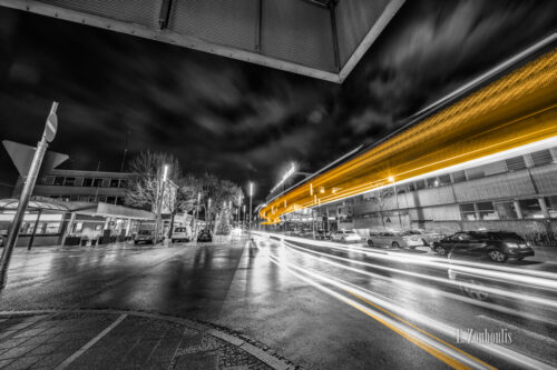 Schwarzweiß-Aufnahme von einem vorbeifahrenden Bus am Bahnhof in Böblingen. Gelbe und rote Lichtschweife kennzeichnen den Verkehr vor dem Mercaden-Einkaufszentrum