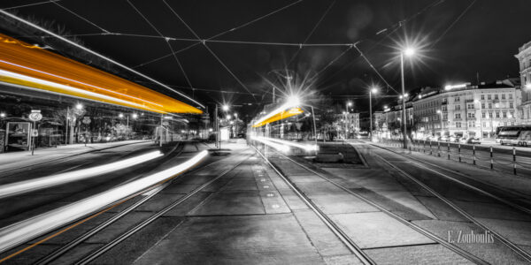 Schwarzweiß-Fotografie am Karslplatz in Wien mit vorbeifahrenden Straßenbahnen in gelb.