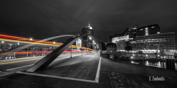 Fotografie am Sandtorkai in Hamburg am Hafen bei Nacht mit Blick auf die Elbphilharmonie. Schwarz Weiß Bild mit gelben und roten Light Trails des vorbeiziehenden Verkehrs