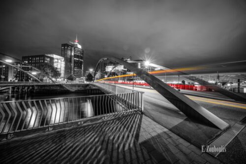 Bild am Sandtorkai in Hamburg am Hafen bei Nacht mit Blick auf die Elbphilharmonie. Schwarz Weiß Bild mit gelben und roten Light Trails des vorbeiziehenden Verkehrs