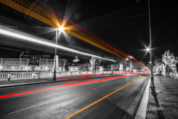 Auf der Brücke Ponte Vittorio Emanuele in Rom bei Nacht mit dem vorbeiziehenden Verkehr, die Lichtschweife hinterlässt. Im Hintergrund ist die Kuppel des Vatikan zu sehen.