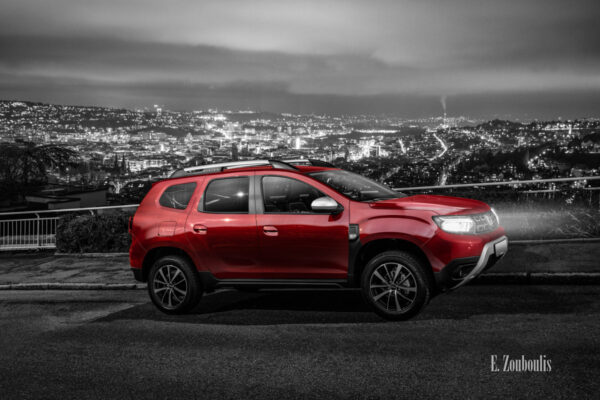 Bild eines roten Dacia Duster bei Nacht. Im Hintergrund ist die Stuttgarter Skyline zu sehen