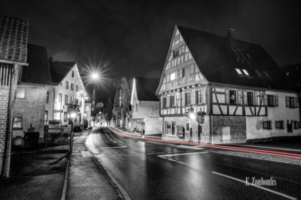 Nachtaufnahme in Aidlingen bei Böblingen. Zu sehen ist die Hauptstraße auf der einige Fachwerkhäuser zu finden sind. Davor sind rote Lichtschweife, die den Verkehr kennzeichnen
