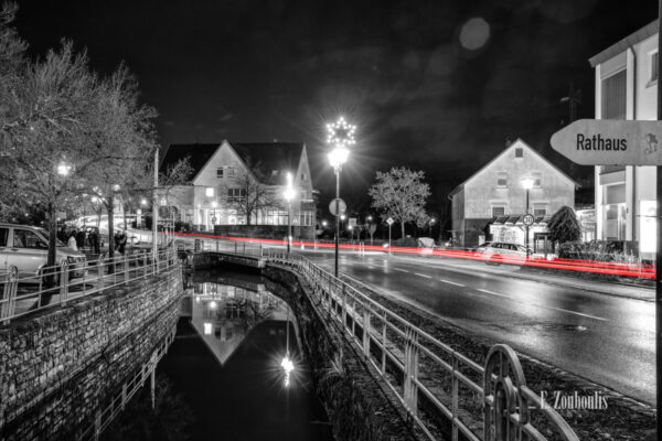 Nachtaufnahme in Aidlingen bei Böblingen. Zu sehen ist die Hauptstraße und die Aid. Entlang der Straße sind rote Lichtschweife, die den Verkehr kennzeichnen