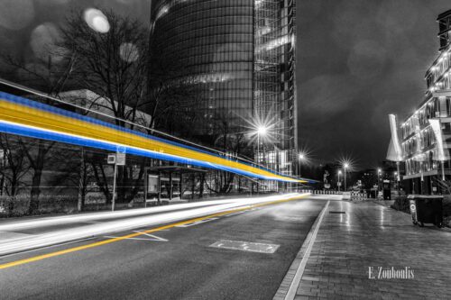 Nachtaufnahme am Post Turm in Bonn mit Blick auf die DHL Hauptzentrale bei Nacht. Zu sehen sind die gelben und blauen Light Trails des vorbeiziehenden Verkehrs vor der gleichnamigen Bushaltestelle an der Charles-de-Gaulle Straße.