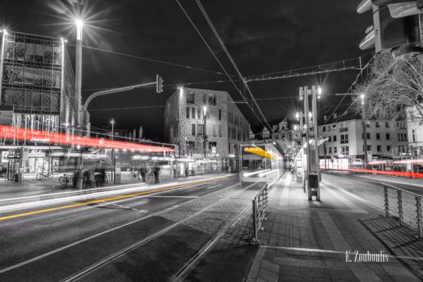 Nachtaufnahme am Konrad-Adenauer-Platz in Bonn bei Nacht. Zu sehen ist der nächtliche Verkehr, der an der gleichnamigen Haltestelle vorbeizieht und rote und gelbe Light Trails hinterlässt